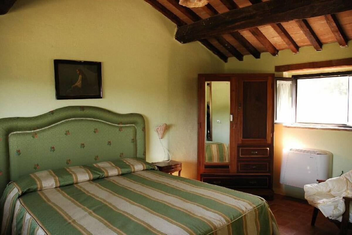 Una habitación con cama, armario, espejo y ventana.