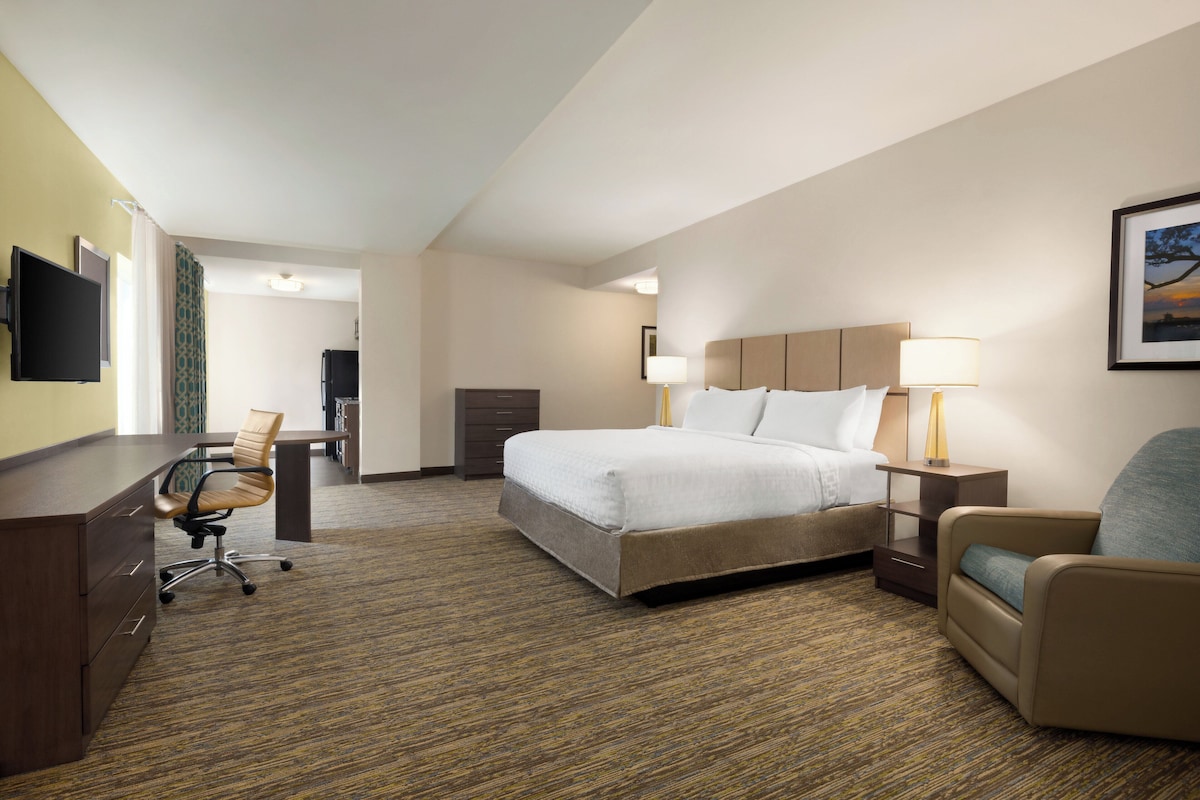 Una habitación de hotel con una cama, un escritorio, una silla y un televisor.