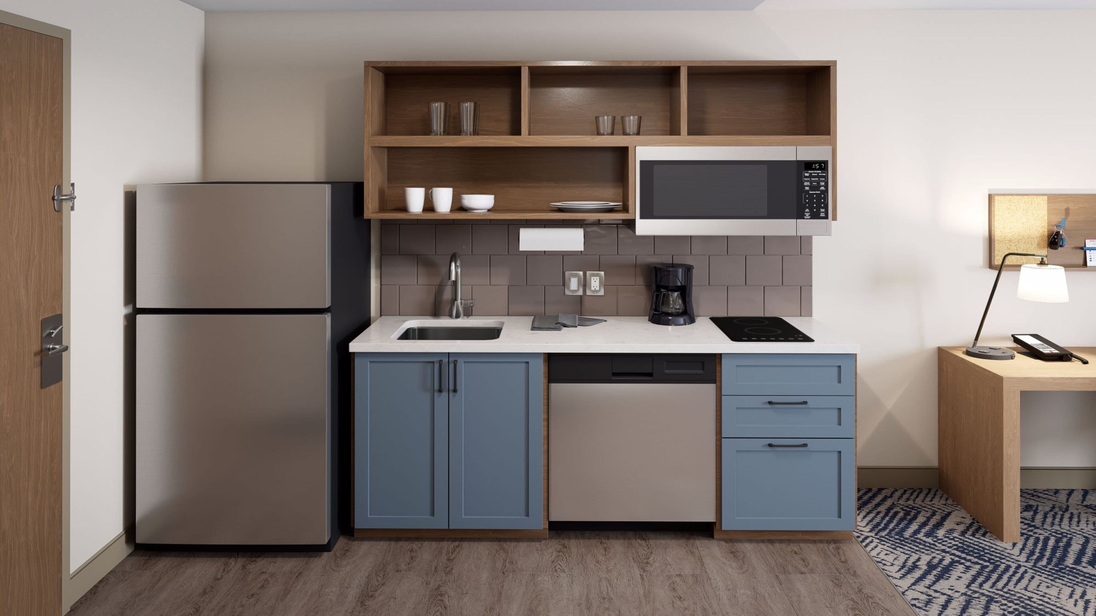 Cocina compacta equipada con refrigerador, microondas, pileta y cafetera.