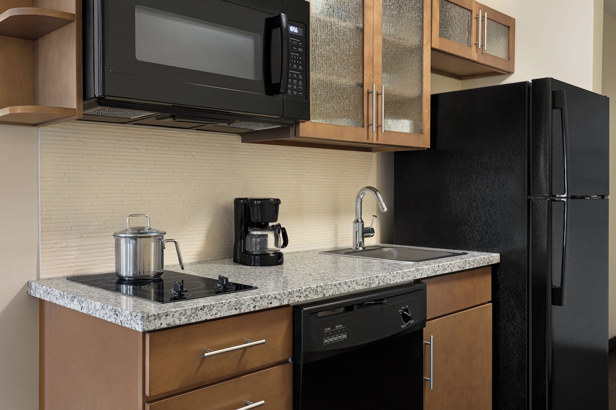 Una cocina equipada con microondas, cafetera, fregadero, lavavajillas y un refrigerador negro.