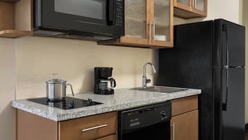 Cozinha com geladeira preta, micro-ondas, cafeteira e lava-louças.