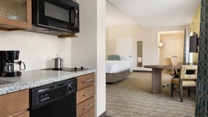 Quarto de hotel com cozinha compacta, uma cama, área de refeições e televisão.