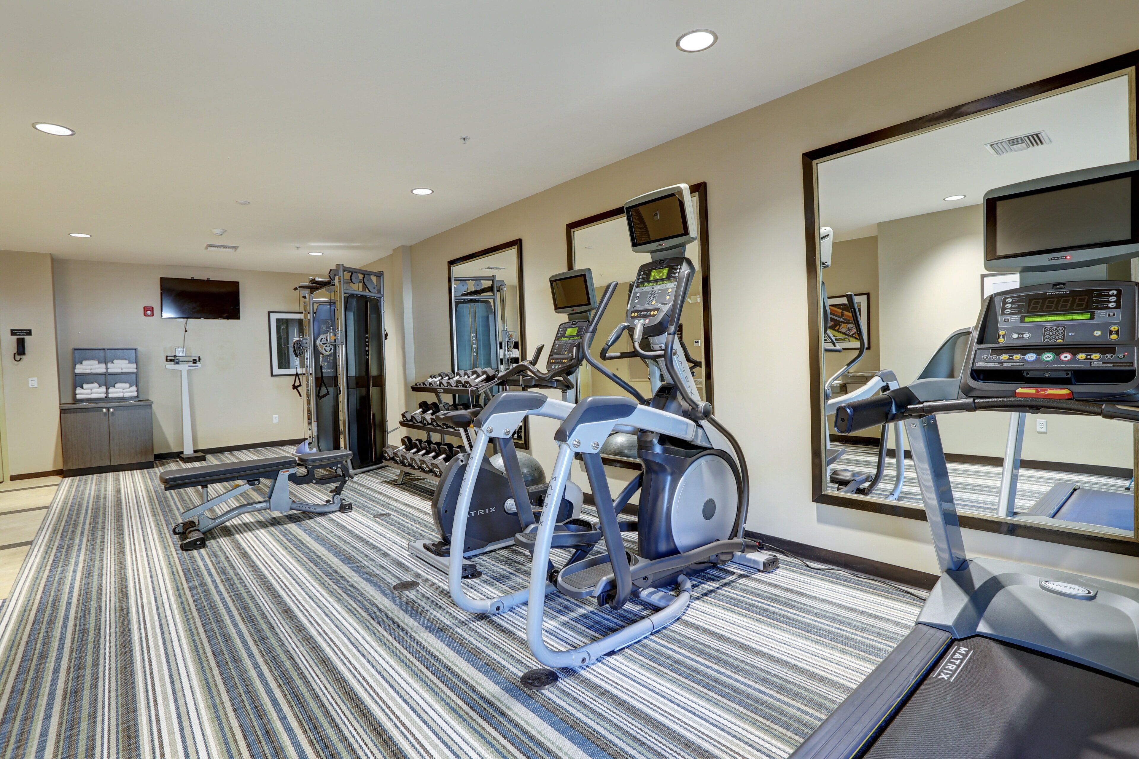 A hotel gym with treadmills, elliptical machines, and weight equipment.