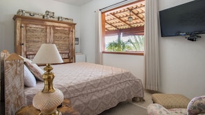 Une chambre à coucher avec un lit, une lampe, une armoire, un téléviseur et une fenêtre avec des rideaux.