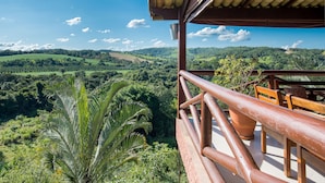Un balcon offrant une vue sur de luxuriantes collines verdoyantes et un ciel bleu azur.