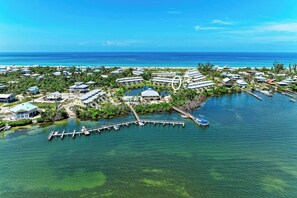 An aerial view of a coastal resort with multiple buildings, a marina, and clear blue waters. - LGI HIDEAWAY! Includes golf cart & pool access! (Placida)