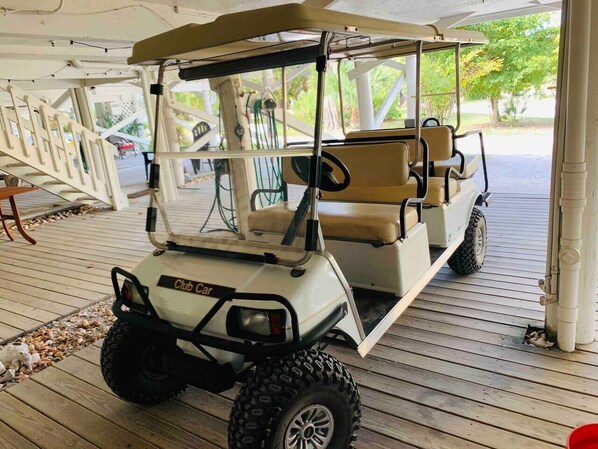 A golf cart with a beige seat and black tires parked on a wooden deck. - LGI HIDEAWAY! Includes golf cart & pool access! (Placida)