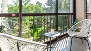 A balcony with two white wicker chairs, a small round table with a white mug, and a view of a green landscape through large windows. - ✨Mountain Suite ✨ stylish apartment with WiFi and Parking 🅿️ (Seynod)
