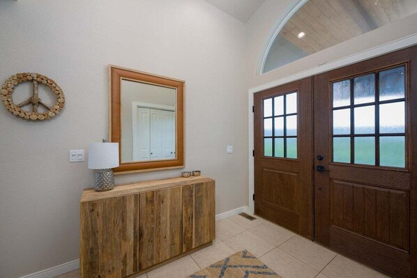 A hallway with a wooden console, a mirror, a peace sign decoration, and a door with frosted glass panels. - Remodeled, Hot Tub, Amazing Views, Great Location (Pagosa Springs)