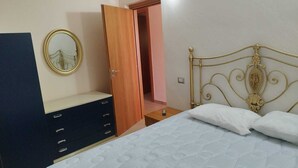 Une chambre à coucher comprenant un lit, une commode, un miroir et une porte donnant sur une autre pièce.