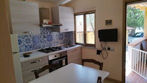 Une cuisine de taille réduite, équipée d’une cuisinière à gaz, d’un évier et d’une fenêtre.
