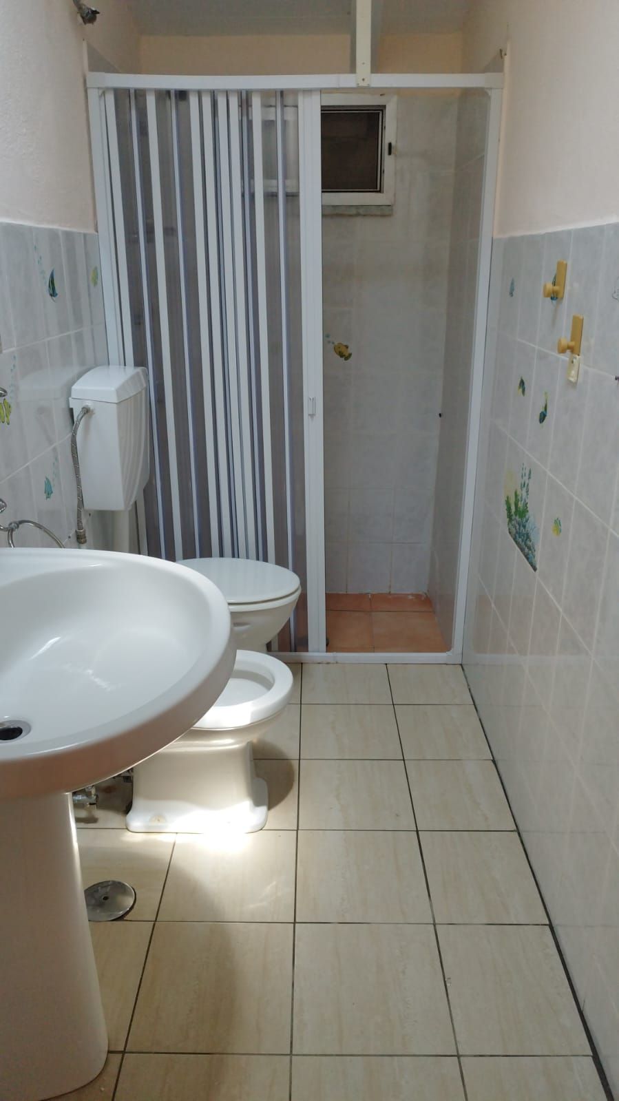 A bathroom with a toilet, a sink, and a shower area.