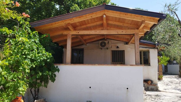 Un bâtiment doté d’un toit en bois, d’une façade blanche et d’une fenêtre.