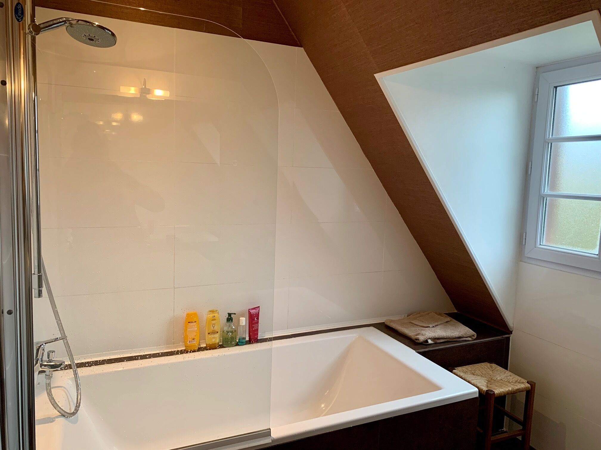 A modern bathroom with a large bathtub, a shower, and a window.