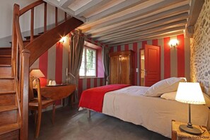 A bedroom with a wooden staircase, a desk with a lamp, a bed with a red blanket, and striped walls. - Le Verger - Le Plessis (Colombiers)