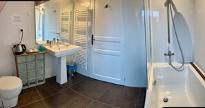 A bathroom with a white sink, mirror, and bathtub. There is a towel rack and a toilet. - Le Verger - Le Plessis (Colombiers)