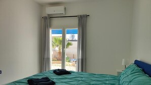 Une chambre avec un lit, une fenêtre avec des rideaux et un appareil de climatisation.