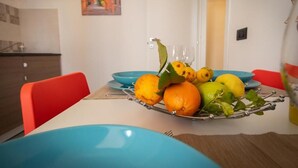 Une table à manger avec un panier de fruits, des assiettes bleues et des chaises rouges.