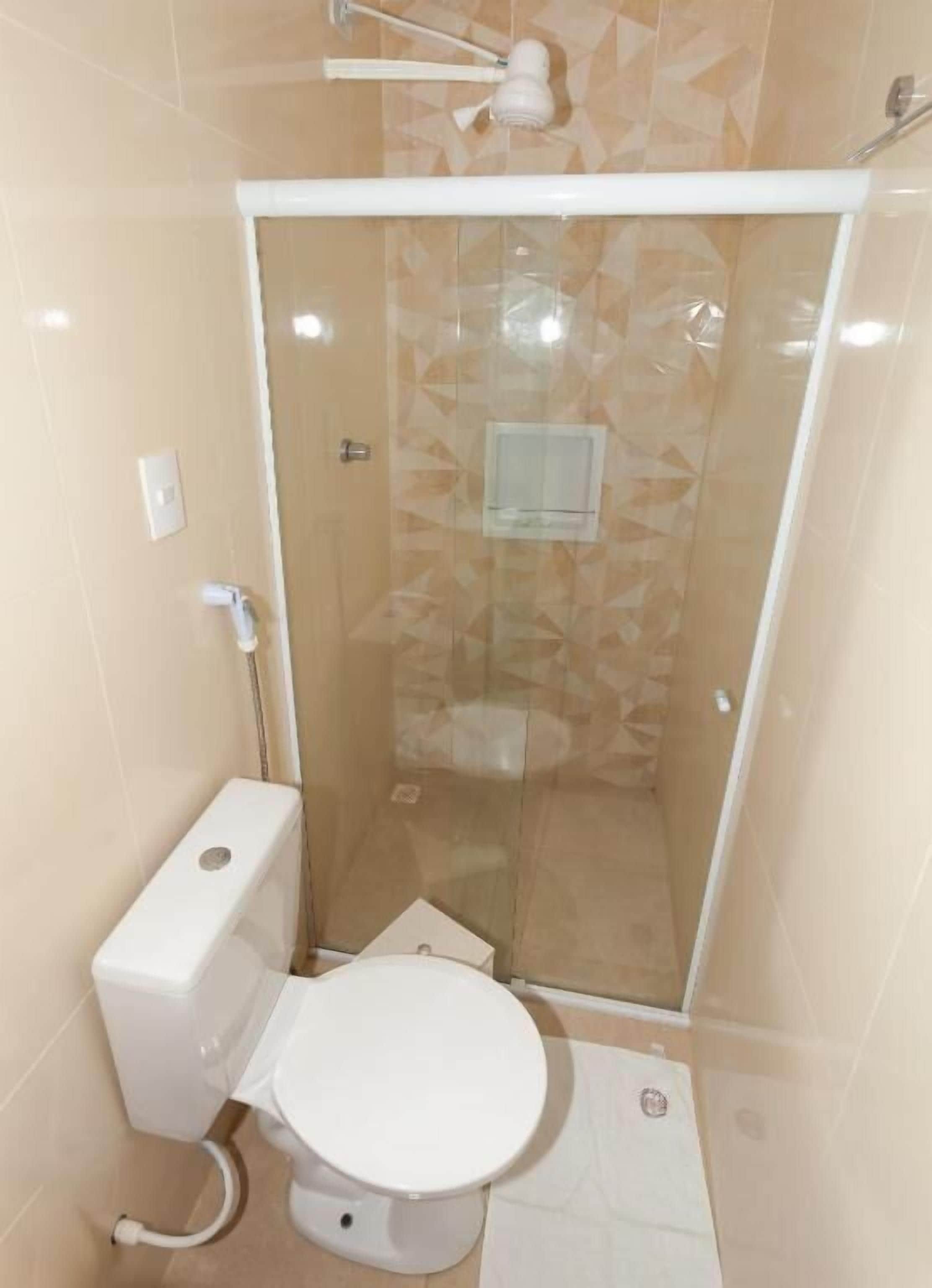 A small, enclosed shower stall with a glass door, a toilet, and a towel rack.