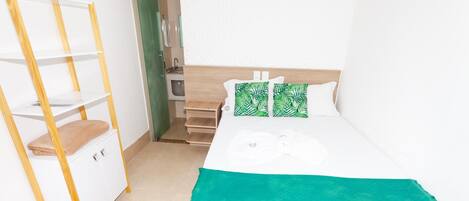 Una camera da letto con un letto, un armadio in legno e una coperta verde.