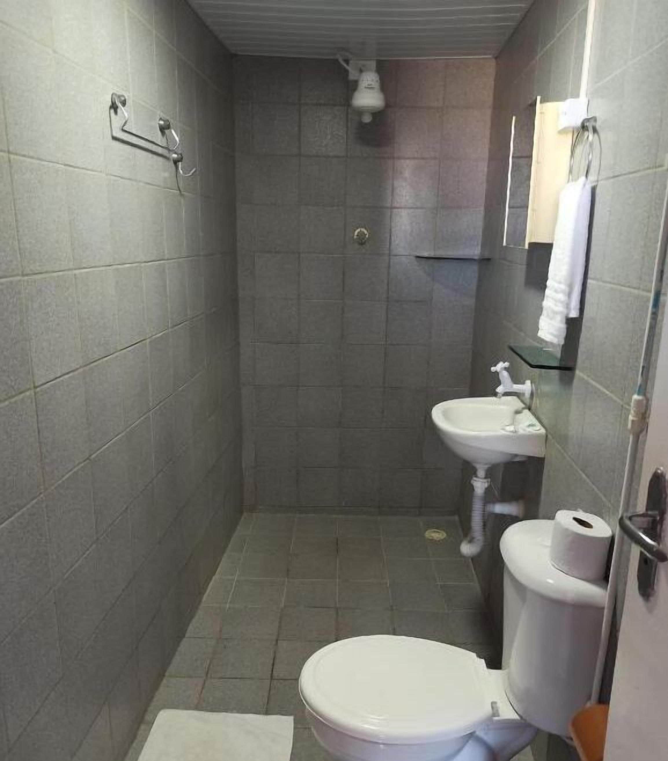 A small, tiled bathroom with a toilet, sink, and shower.