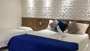 Ein Hotelzimmer mit zwei Betten, einer Zierwand und einer blauen Bettdecke.