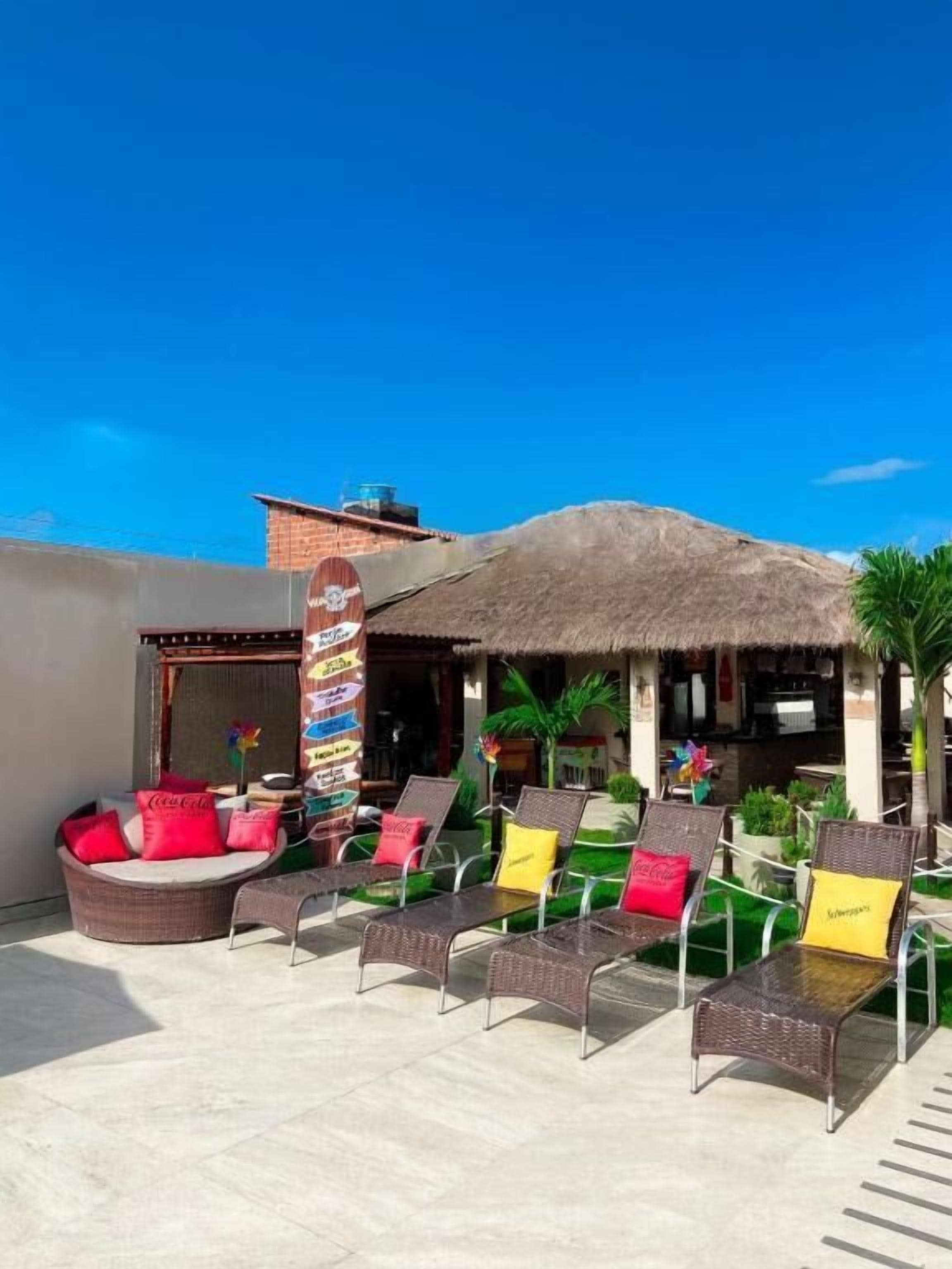 An outdoor seating area with wicker chairs and a thatched roof structure.