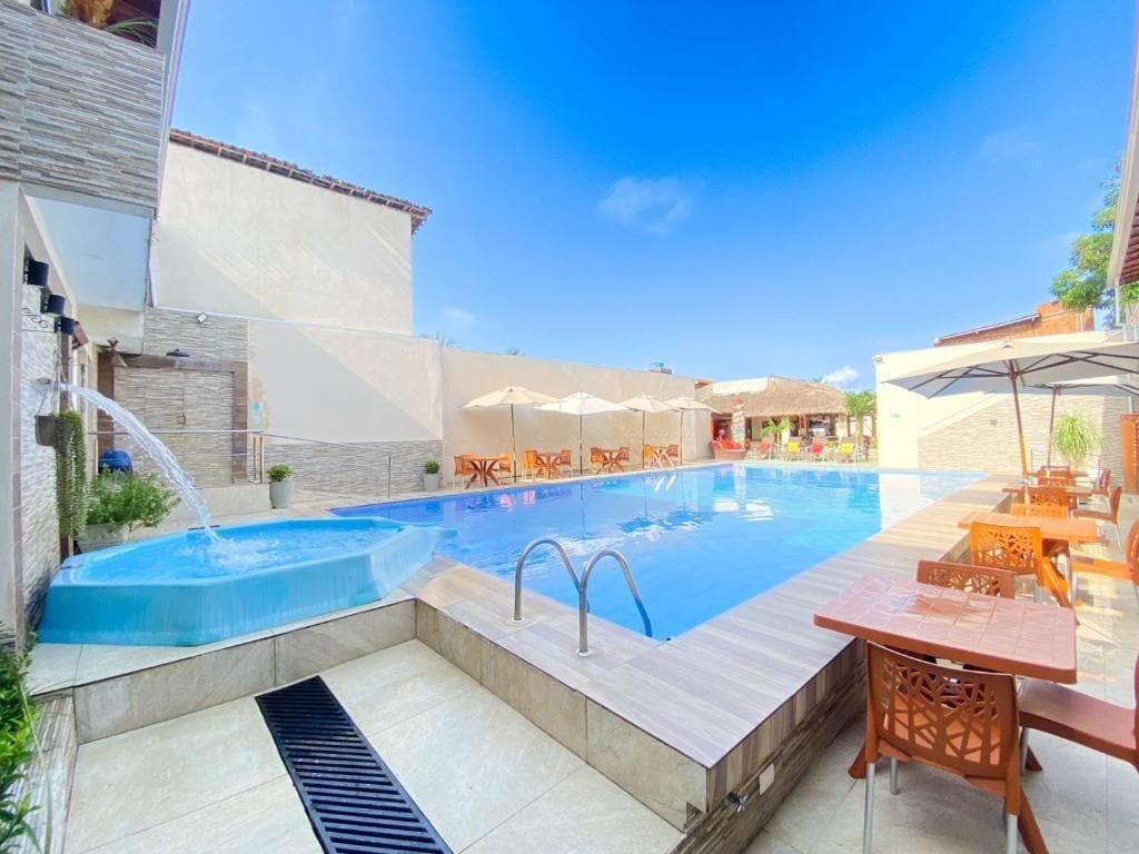 Une piscine agrémentée d’un élément décoratif aquatique, entourée de coins salon et de parasols.