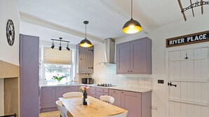 A kitchen with a wooden table and chairs, a window with plants, and a sign reading "RIVER PLACE." - An immaculately presented, 2 bedroom property with river views. (Gargrave)