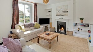 A living room with a sofa, coffee table, fireplace, TV, and a view of the outdoors. - An immaculately presented, 2 bedroom property with river views. (Gargrave)