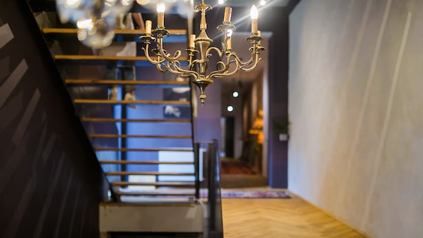 A staircase with a wooden finish and a chandelier with multiple lights.