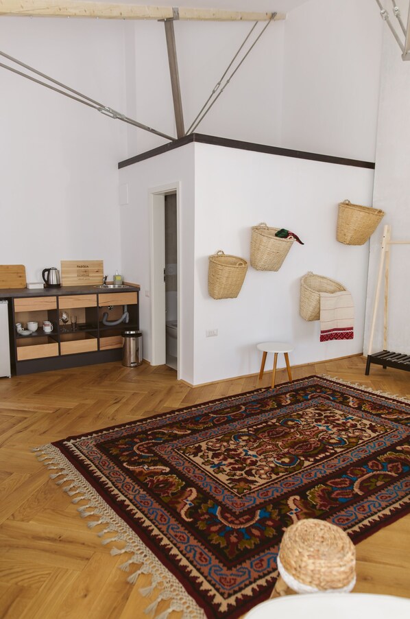 A modern kitchen with wooden cabinets, a built-in sink, and a herringbone-patterned rug. - Camino Home2 (Cluj-Napoca)