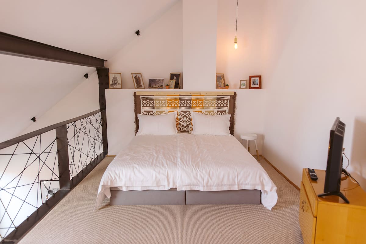 Une chambre à coucher avec un lit, une petite table de chevet, un téléviseur et un escalier.