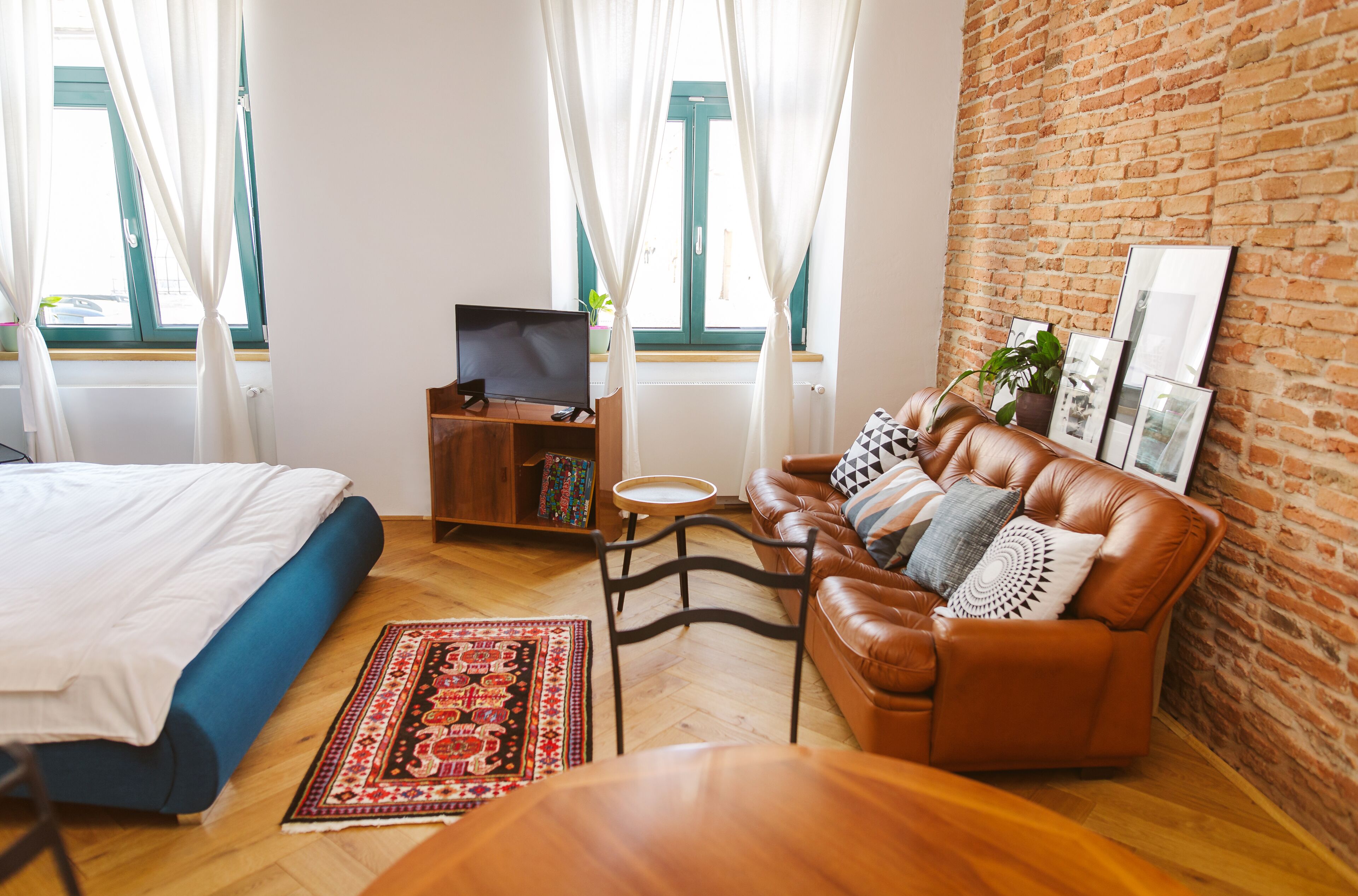 A cozy living room with a leather sofa, a wooden coffee table, a bookshelf, and a TV.