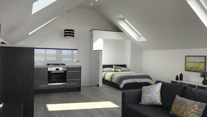 Quarto amplo estilo loft moderno com claraboia, cozinha compacta e sala de estar com sofá e almofadas.