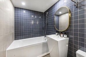 A modern bathroom with a bathtub, a sink with toiletries, and a mirror. - YAJA Hotel Gimhae (Gimhae)