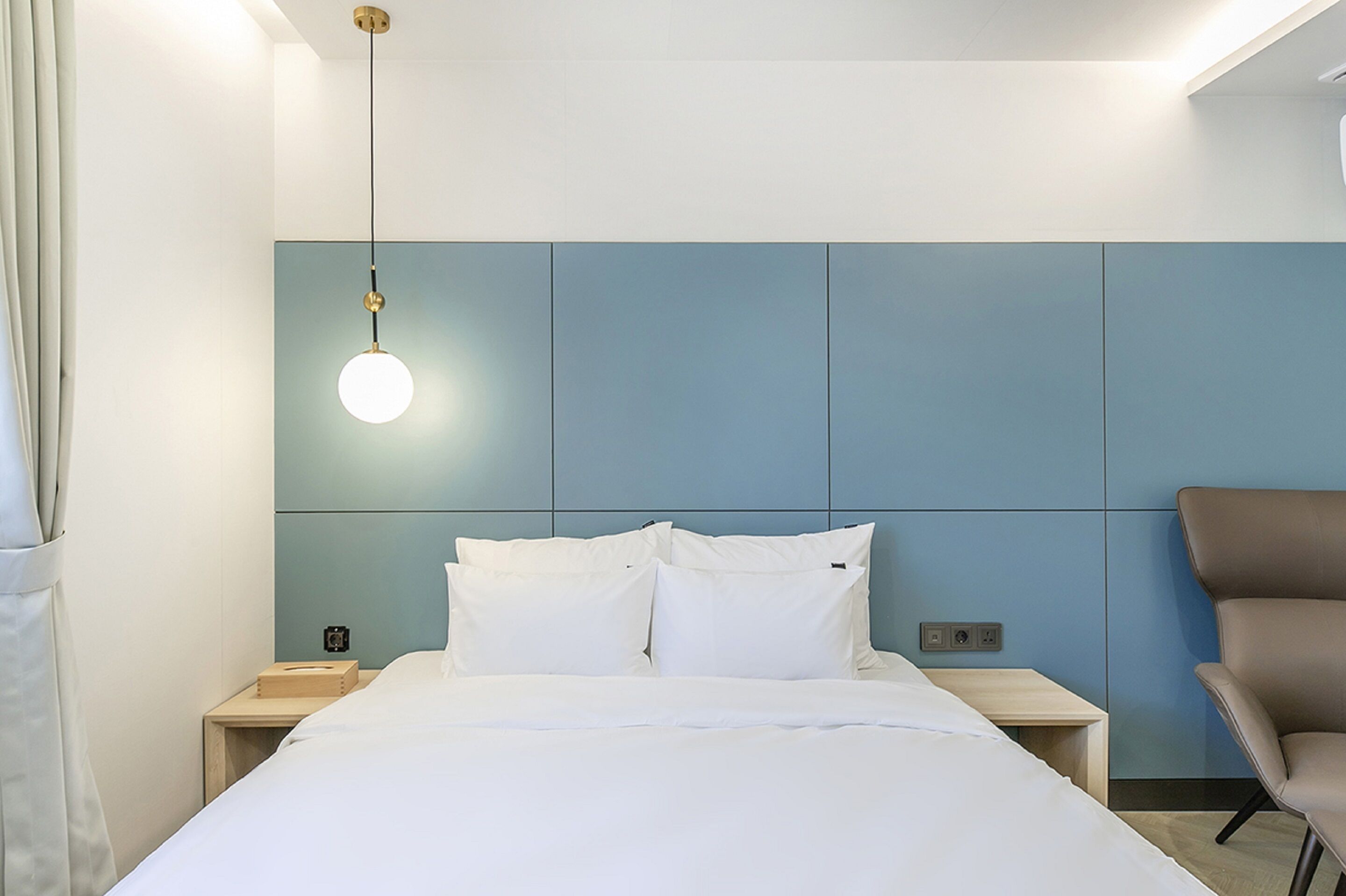 Une chambre d’hôtel moderne équipée d’un lit, de tables de chevet, d’un bureau et d’une chaise.