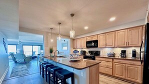 Une cuisine moderne avec des meubles en bois, un îlot central doté de tabourets de bar et un coin repas offrant une vue agréable.