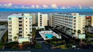 Un hôtel à plusieurs étages, doté d’une piscine et offrant une vue sur la plage.