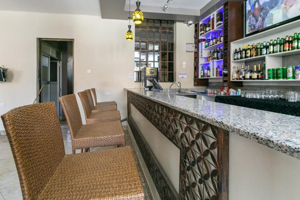 A bar area with wicker chairs, a bar counter, and shelves with bottles.
