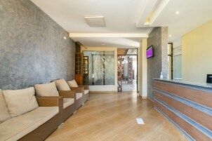 A reception area with a reception desk, a seating area with wicker sofas, and a view of the lobby.