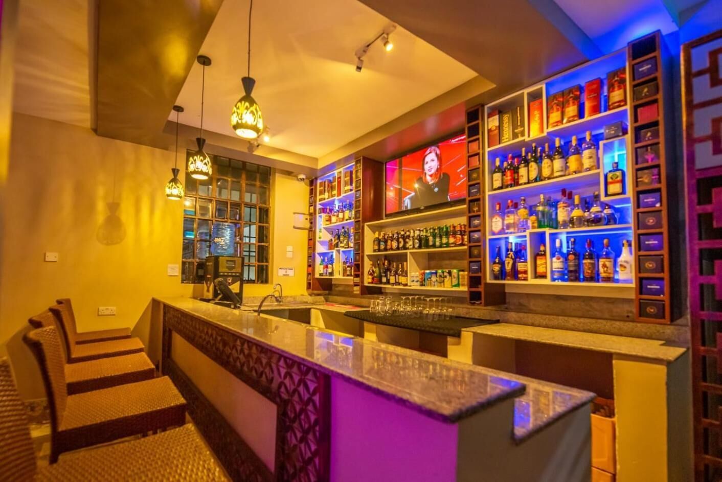 A bar area with seating, a counter, and shelves of liquor bottles.