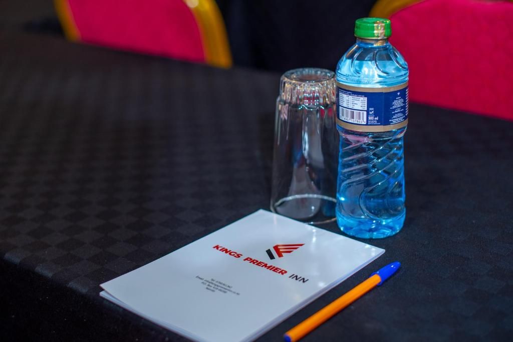 A table with a bottle of water, a glass, a pen, and a menu.