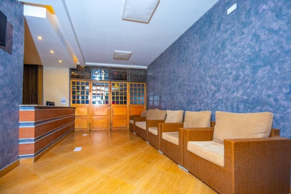 Een receptie met een houten balie, rieten banken en een blauwe wand met structuur.