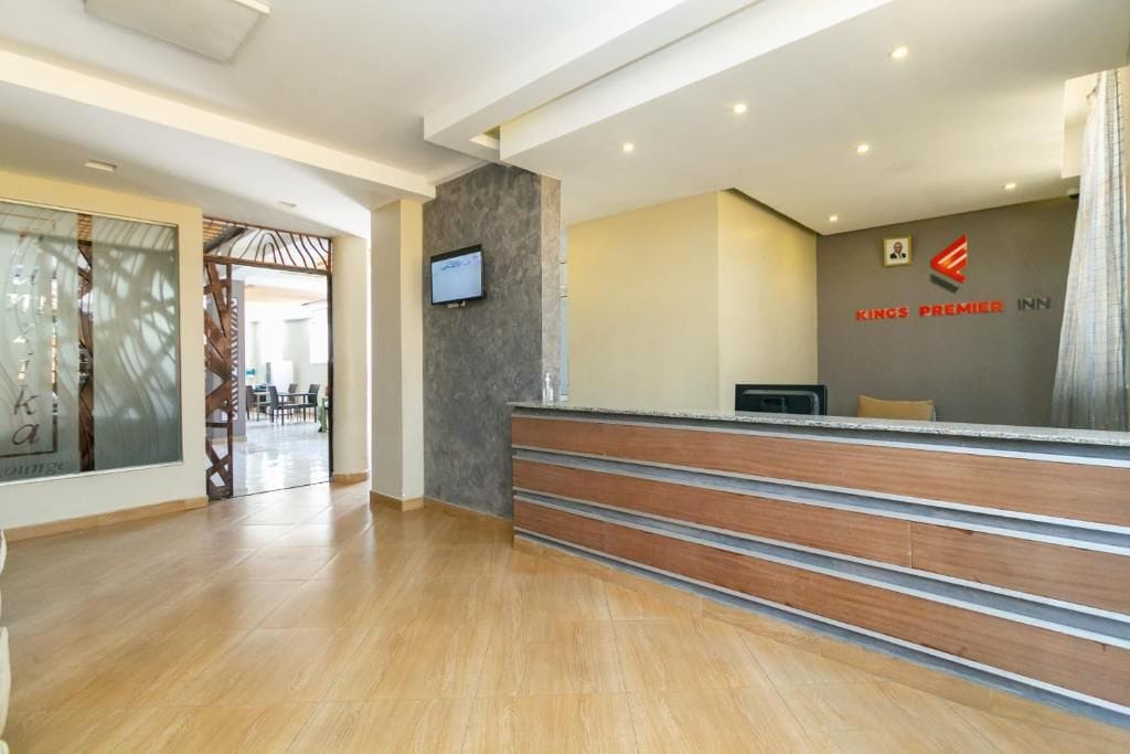 Ein Hotel-Empfangsbereich mit modernem Design, einer Rezeption und einem an der Wand befestigten Fernseher.