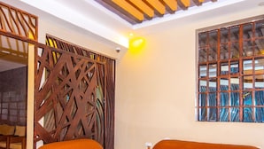 A room with two orange leather sofas, a wooden coffee table, and a wooden ceiling with slats. - Kings Premier Inn (Mlolongo)