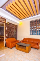 A room with two orange leather sofas, a wooden coffee table, and a wooden ceiling with slats.