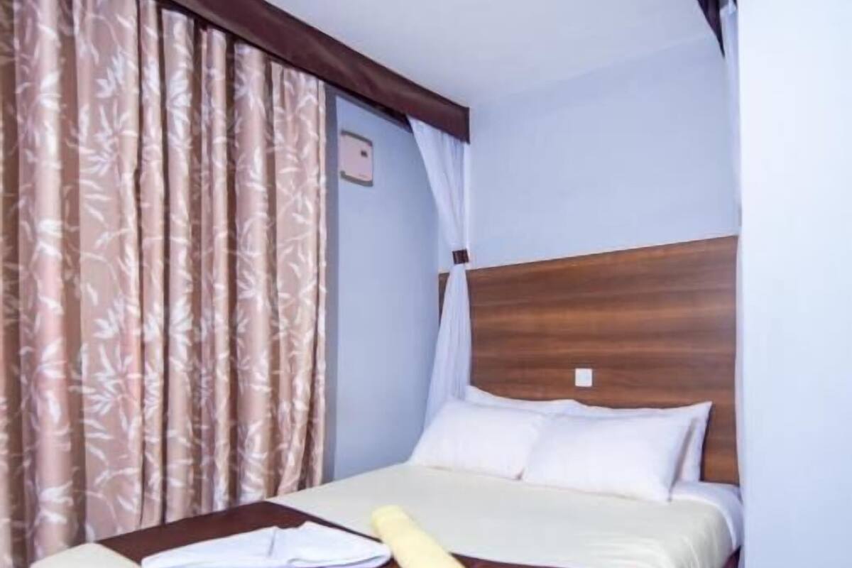 A hotel room with a bed, curtains, and a headboard.