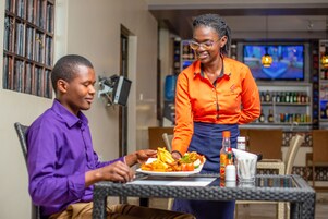 A person serving food to another person at a table in a restaurant setting.