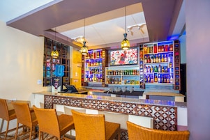 A bar area with wicker chairs, a counter, and shelves of liquor bottles.